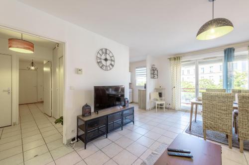 un salon avec une télévision et une horloge murale dans l'établissement Chic appart avec parking au centre-ville, à Rouen