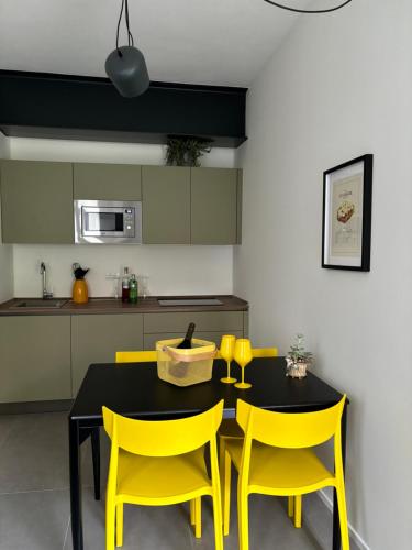 a kitchen with a black table and yellow chairs at Il Giardino Segreto in Faggeto Lario 