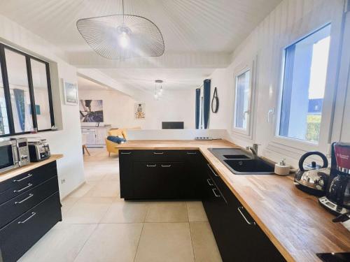 une cuisine avec des armoires noires et un comptoir dans l'établissement Maison lumineuse avec jardin entre plages de Cap-Coz et Beg-Meil, proche activités nautiques - FR-1-481-173, à Fouesnant