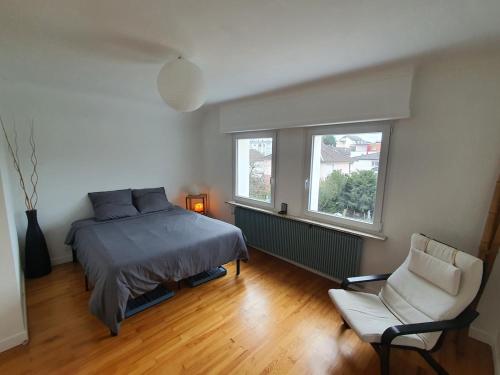 - une chambre avec un lit, une chaise et deux fenêtres dans l'établissement Maison Calme quartier central, à Haguenau