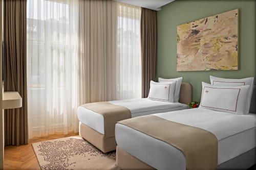two beds in a room with a window at Casa Foscolo Hotel, Istanbul, a Member of Design Hotels in Istanbul
