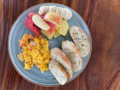 a blue plate of food with eggs fruit and bread at Minca Sintropia - Sustainable Lodge & Organic Coffee Finca in Minca