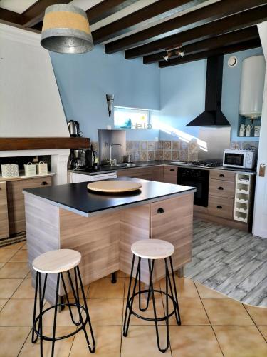 une cuisine avec un îlot et deux tabourets de bar dans l'établissement Joli Cocon,5 min du zoo,au calme,jeux pour enfants, à Châteauvieux