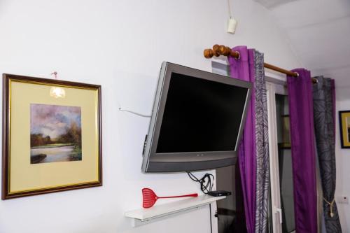 a flat screen tv on a wall with purple curtains at Zvezdana noc in Zvezdara