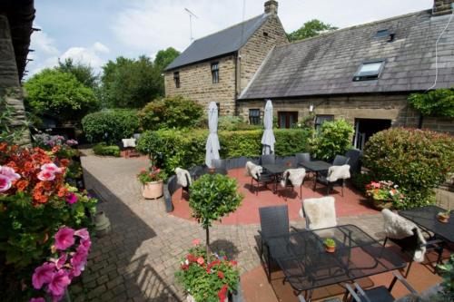 a patio with chairs and umbrellas in front of a building at The Plough Inn in Hathersage