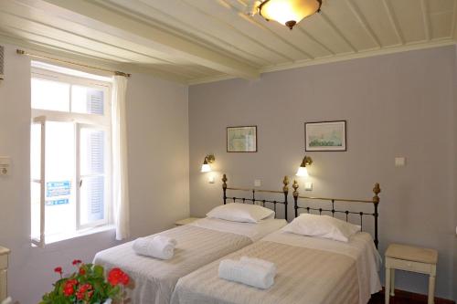 two beds in a room with a window at Pension Eva in Chania Town