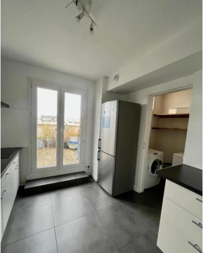 une cuisine vide avec un réfrigérateur et une fenêtre dans l'établissement LAGRIVE - Appartement avec balcon, à Reims