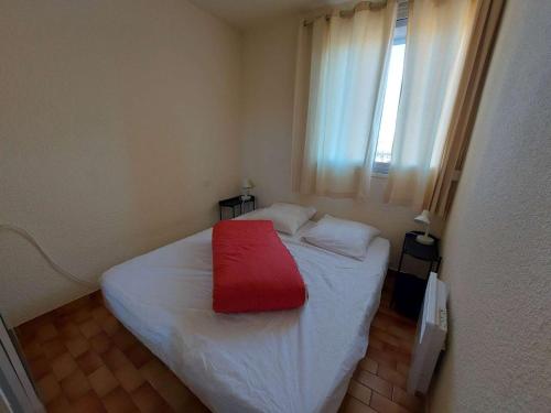- une petite chambre avec un lit blanc et une couverture rouge dans l'établissement 2 pièces avec terrasse et parking privé, Grau d'Agde - FR-1-423-197, au Grau-dʼAgde