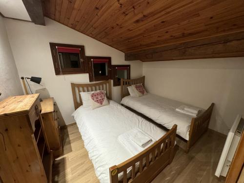 deux lits dans une chambre avec plafonds en bois dans l'établissement Apartment L Haut Sapin, sleeps 8, à Morzine