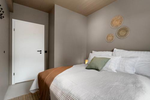a bedroom with a white bed with a green pillow on it at Apartment by the sea in the heart of Hafnarfjörður in Hafnarfjördur