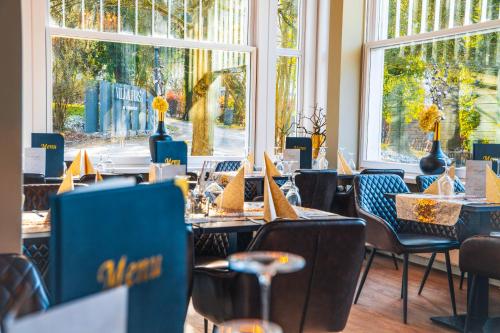a dining room with tables and chairs and windows at VILLA FIRST im Sophienhof in Königswinter