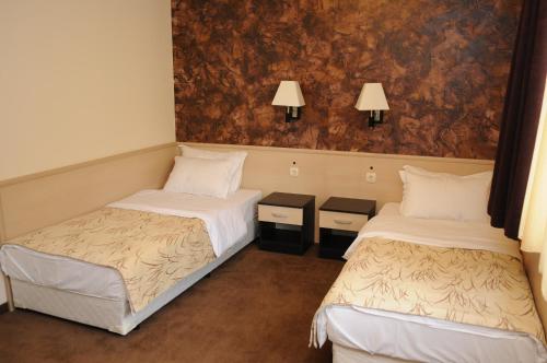 two beds in a room with two lamps on the wall at Hotel Balkan in Botevgrad