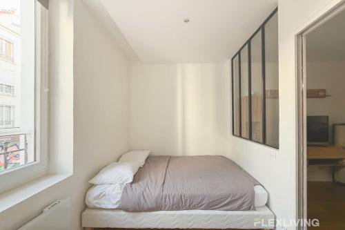 un lit dans une chambre blanche avec une fenêtre dans l'établissement Flexliving - T2 - Montreuil, à Paris