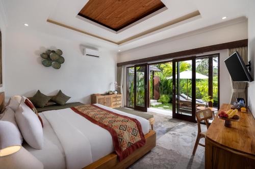 a bedroom with a bed and a desk and a television at Arvanya Villa Ubud in Tegalalang