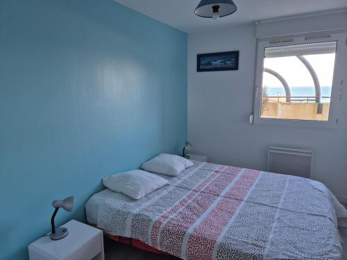 une chambre bleue avec un lit et une fenêtre dans l'établissement Plage et terrasse à vos pieds, à Perros-Guirec