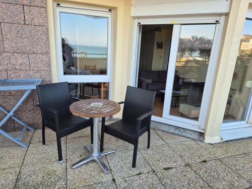 une table et des chaises sur une terrasse avec une fenêtre dans l'établissement Plage et terrasse à vos pieds, à Perros-Guirec