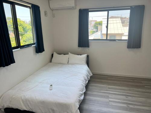 a bed in a room with two windows at FabulousOdawara in Odawara