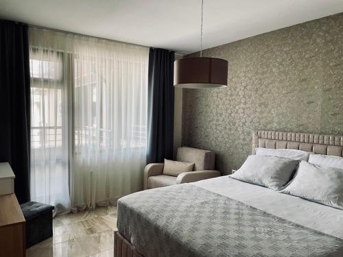a bedroom with a bed and a chair and a window at Beach Residence Pomorie in Pomorie