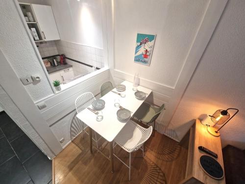 - une table blanche avec deux chaises et un ordinateur portable dans l'établissement Appartement Cosy, Vue MontBlanc, Chamonix Centre, à Chamonix-Mont-Blanc