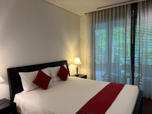 a bedroom with a large white bed with red pillows at Kata Gardens Luxury Apartment 8B at Kata Noi Beach in Kata Beach