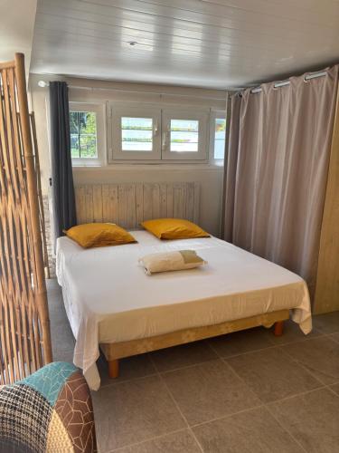 a large bed in a room with two windows at Studio lumineux tout équipé in Rivière-Salée