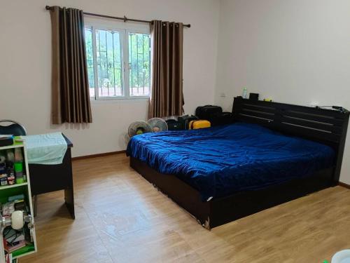a bedroom with a bed with a blue comforter at บ้านสวนสบายใจโฮมสเตย์ ใกล้มหาวิทยาลัยแม่ฟ้าหลวง ห่างเมือง 20 กม ห่างถนน 2 กม in Ban Huai Pa Phlu