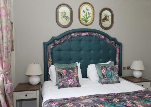 a bedroom with a large bed with a blue headboard and pillows at The Castle Of Brecon Hotel, Brecon, Powys - The Coaching Inn Group in Brecon