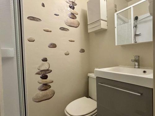 La salle de bains est pourvue de toilettes et de rochers sur le mur. dans l'établissement Appartement 2 pièces, balcon, proche plage et commerces, quartier calme - Argelès-sur-Mer - FR-1-225-685, à Argelès-sur-Mer