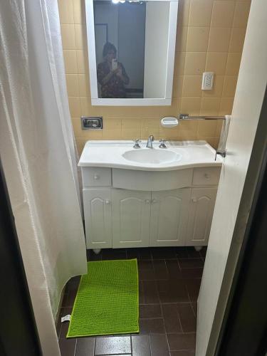 bagno con lavandino, specchio e tappeto verde di Departamento centrico a Trelew