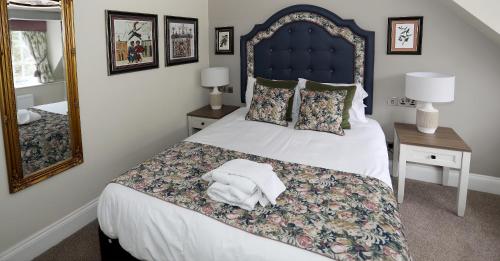 a bedroom with a bed with a blue headboard and a mirror at The Castle Of Brecon Hotel, Brecon, Powys - The Coaching Inn Group in Brecon