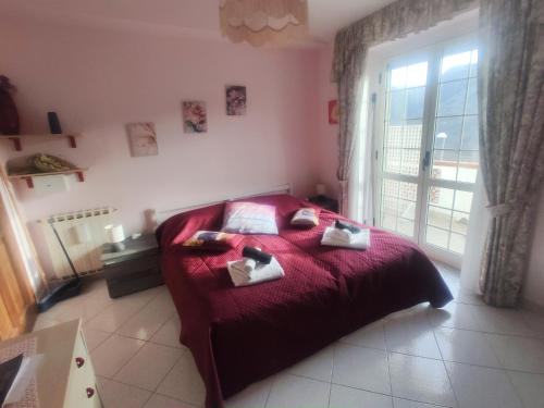 a bedroom with a red bed and a window at Vicky's B&B by V in Papasidero