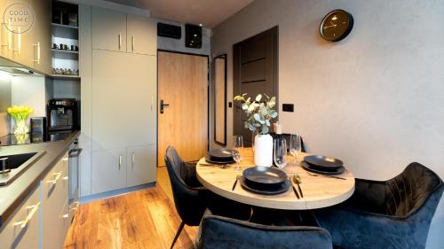 a dining room table with chairs and a clock on the wall at Apartamenty Good Time - Belle View - Centrum in Szklarska Poręba