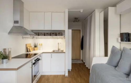 una cucina con mobili bianchi e un divano in una stanza di Du vil elske å bo her! Et lite, men koselig sted med perfekt beliggenhet! a Trondheim