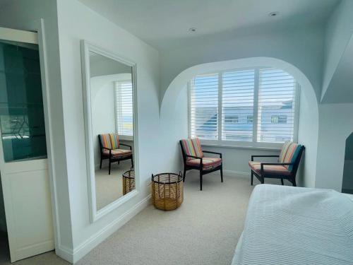 a bedroom with a mirror and two chairs and a table at Baywatch Mawgan Porth Spacious Home sleeps 9, Games room, Parking & Garden in Mawgan Porth