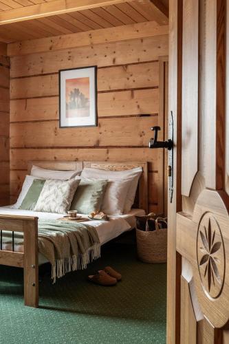 a bedroom with a bed in a wooden cabin at Willa Podhalanka Jacuzzi & sauna - drewniany dom dla 20 osób in Biały Dunajec