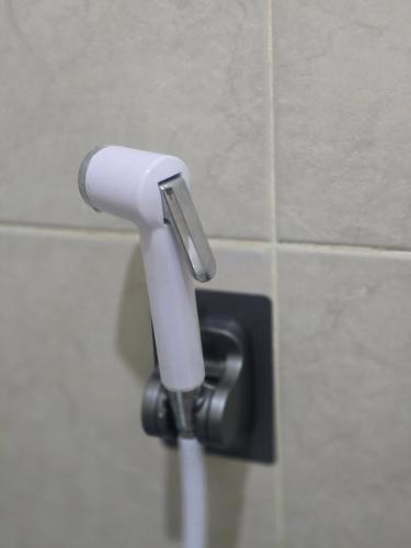 a white toilet paper dispenser on a tiled wall at 209 Cozy apartment with nice fan near skytrain & WiFi in Bangkok