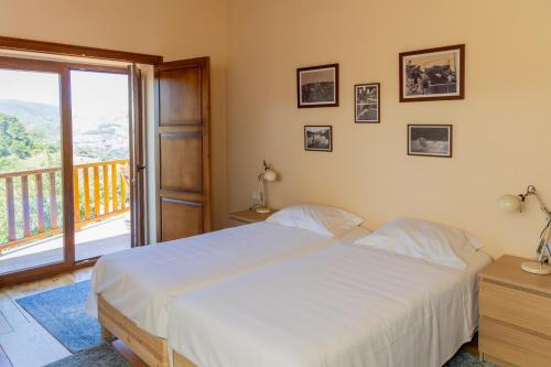 a bedroom with a white bed and a balcony at Casa de Vilarinho in Vilarinho de Cotas