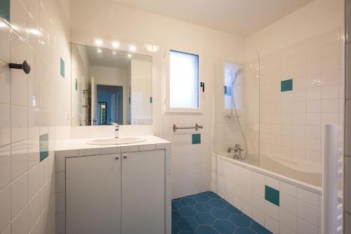 une salle de bain avec un lavabo, une baignoire et un miroir dans l'établissement Villas Indigo 40 personnes, à La Teste-de-Buch
