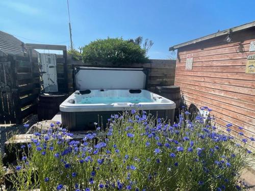 a bath tub in a garden with purple flowers at Baywatch Mawgan Porth Spacious Home sleeps 9, Games room, Parking & Garden in Mawgan Porth