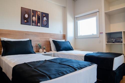 a bedroom with two beds with blue pillows at i5 Hotel Águas Claras in Brasilia