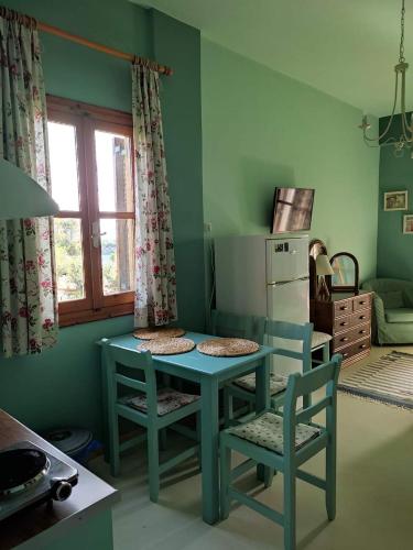 a kitchen with a blue table and chairs and a window at iliolithos rooms in Kardamili