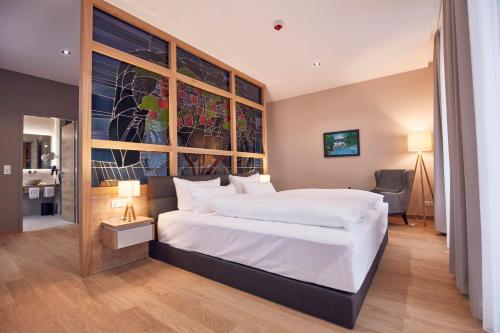 a bedroom with a large bed and a large window at Seehotel Maria Laach in Maria Laach