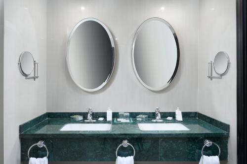 a bathroom with two sinks and two mirrors at Renaissance Caracas La Castellana Hotel in Caracas