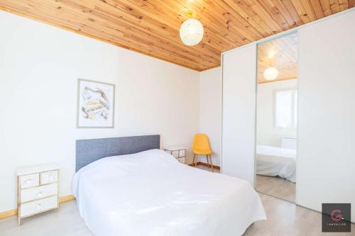 - une chambre avec un lit blanc et un plafond en bois dans l'établissement Maison de Vacances à Biscarrosse – Proche du Lac de Latécoère 5 personnes, à Biscarrosse