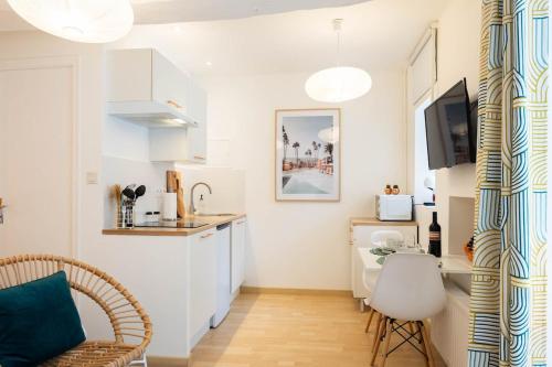 a kitchen with white cabinets and a table in a room at Le Palm Spring - studio cosy en centre-ville in Fougères