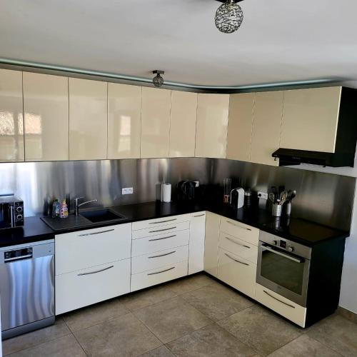 une cuisine avec des armoires blanches et des comptoirs noirs dans l'établissement Jenna, à Grimaud