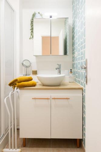 une salle de bain blanche avec un lavabo et un miroir dans l'établissement Le Palm Spring - studio cosy en centre-ville, à Fougères
