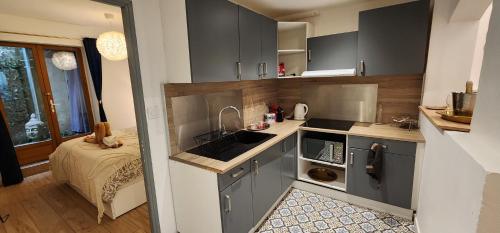 - une cuisine avec des placards gris, un évier et un lit dans l'établissement Sérénité au Palais Suite romantique Jacuzzi, à Avignon