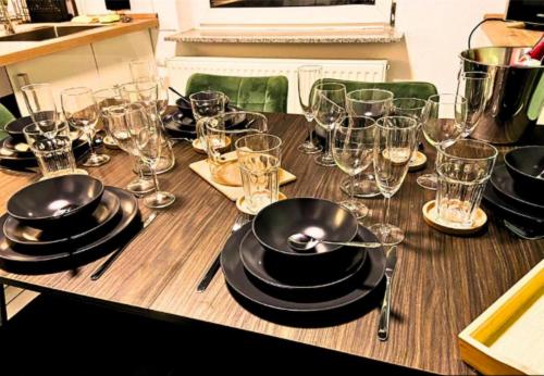 a wooden table with glasses and plates on it at Ferienapartment Saarbrücken Zentrumsnah mit Luxus-Heimkino, Grill, Balkon & Miele Küche in Saarbrücken