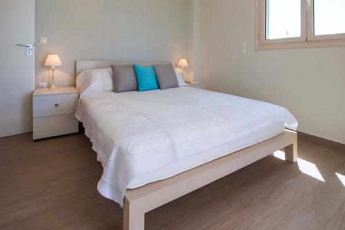 a large white bed in a bedroom with two lamps at Villa Eco Blu in Marathopolis